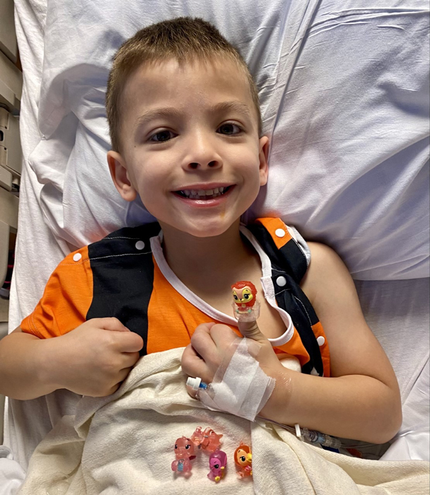 Young boy in a hospital bed smiling with his toy prize