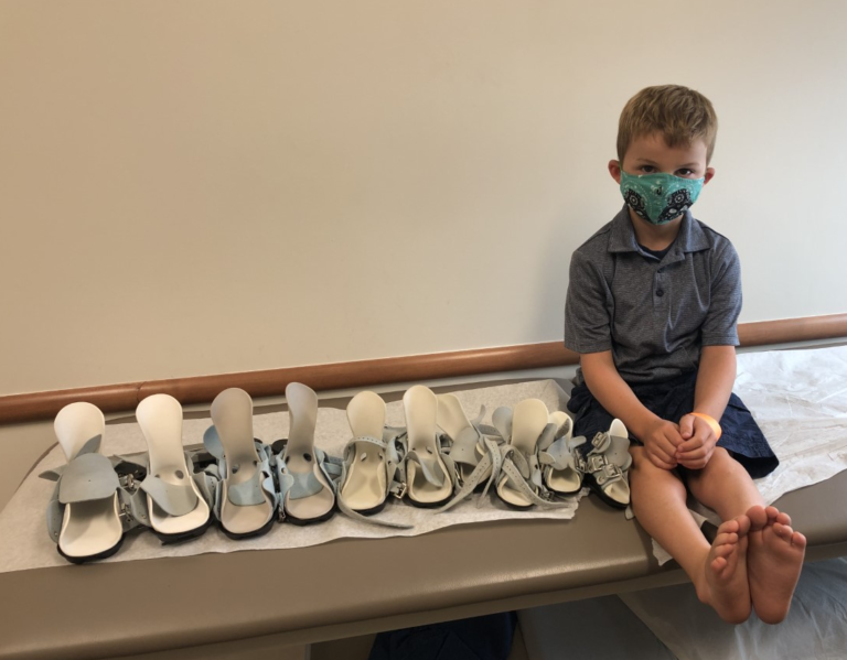Evan sitting next to all of his boots and bars that he donated to needy children with clubfoot