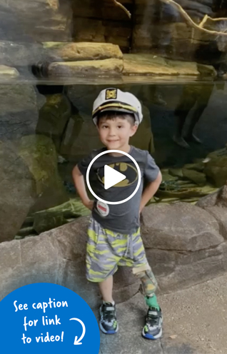 Young boy smiling wearing a ship captain cap in front of an aquarium tank