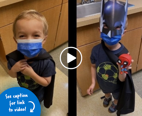An International Center for Limb Lengthening patient wearing a cape and a Batman mask while holding a Spiderman doll