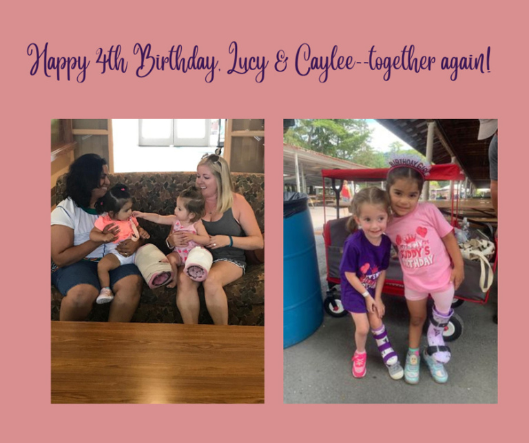 A photo of Lucy and Kaylee at age one interacting while sitting on their mothers