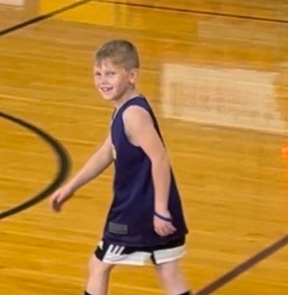 Young boy smiling while walking on an indoor basketball court