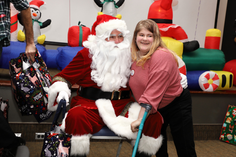 Santa and girl using a forearm crutch smiling