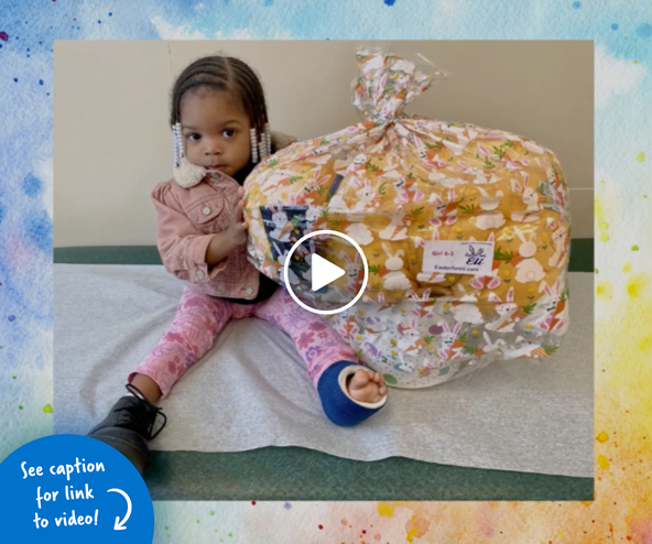 Little girl wearing a leg cast sitting on an examination table with a Easter basket as big as she is
