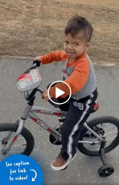 Young boy riding a bike with training wheels