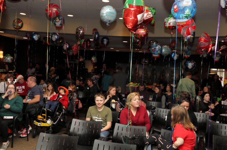 Families sitting in chairs decorated with balloons enjoying the International Center for Limb Lengthening pediatric holiday party