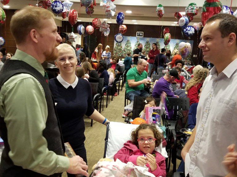 Physician Assistant Chris Fisher talking with patient family at the International Center for Limb Lengthening pediatric holiday party