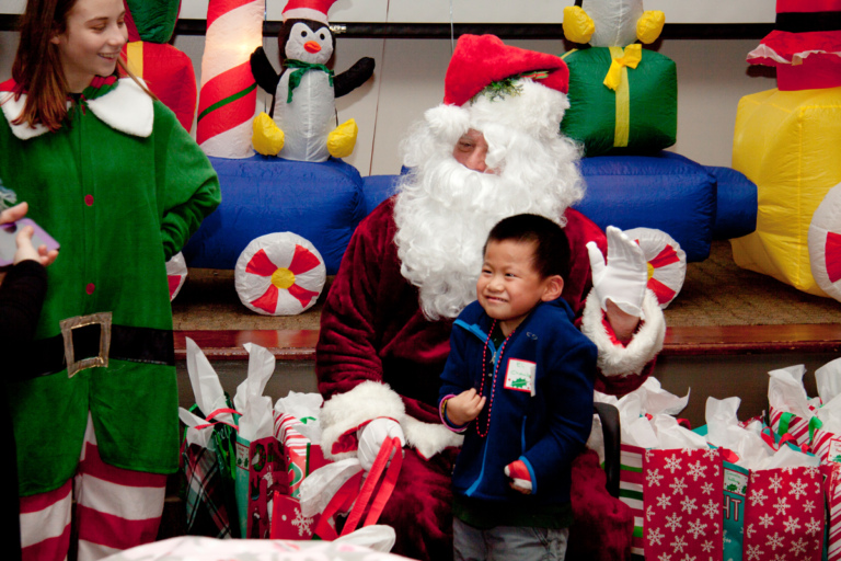 Santa and elf posing with young boy in hand cast at the International Center for Limb Lengthening pediatric holiday party