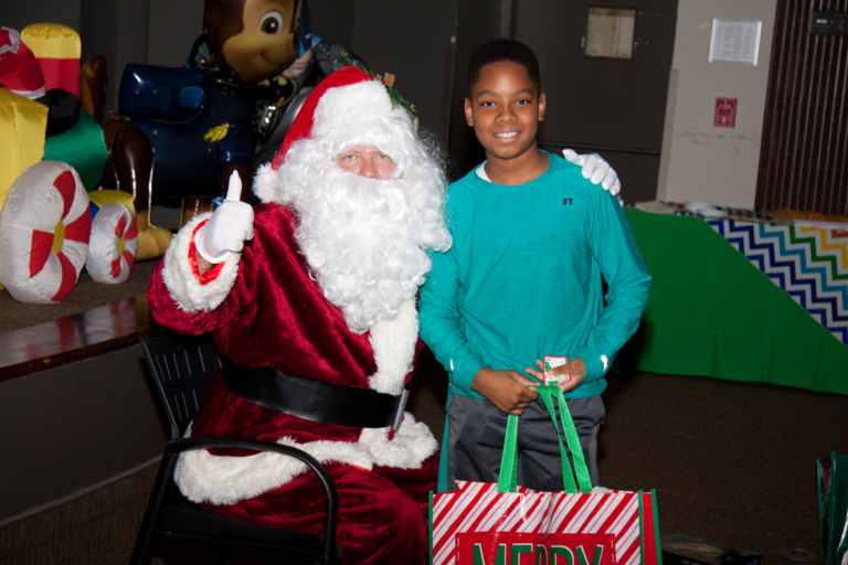 Santa gives a thumbs up with boy with present at the International Center for Limb Lengthening pediatric holiday party