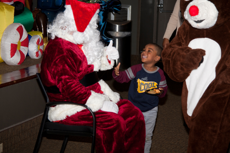 Santa greets young boy with food at the International Center for Limb Lengthening pediatric holiday party