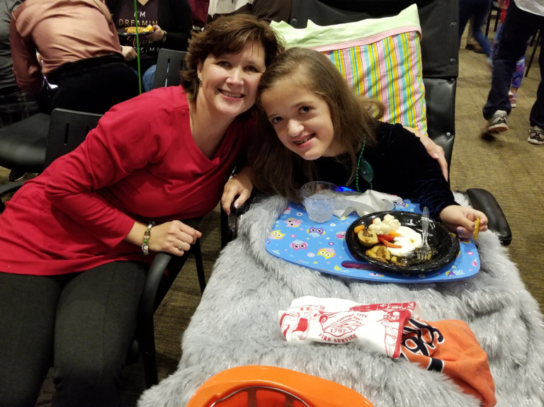 Mom and daughter in wheelchair enjoying food at the International Center for Limb Lengthening pediatric holiday party