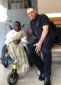 Buru in a wheelchair smiling with Dr Christof Radler