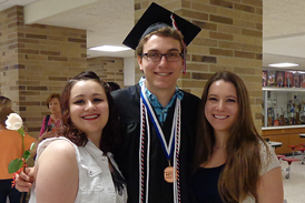 Chase in graduation cap and gown with his two sisters