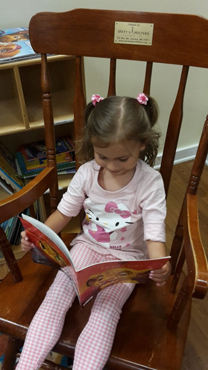 Anicka using her treated hand holding open a book on a rocking chair