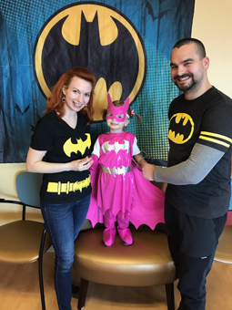 Anicka dressed in a pink Bat Girl costume with her parents in Batman t-shirts for a patient Batman party