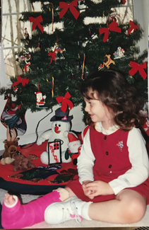 Katia as a young girl in a cast by a Christmas tree