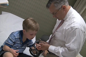 Dr. Shawn Standard checking the hand of a boy patient who is wearing an external fixator on his arm in the International Center for Limb Lengthening clinic