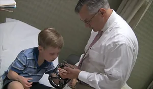 Dr. Shawn Standard checking the hand of a boy patient who is wearing an external fixator on his arm in the International Center for Limb Lengthening clinic