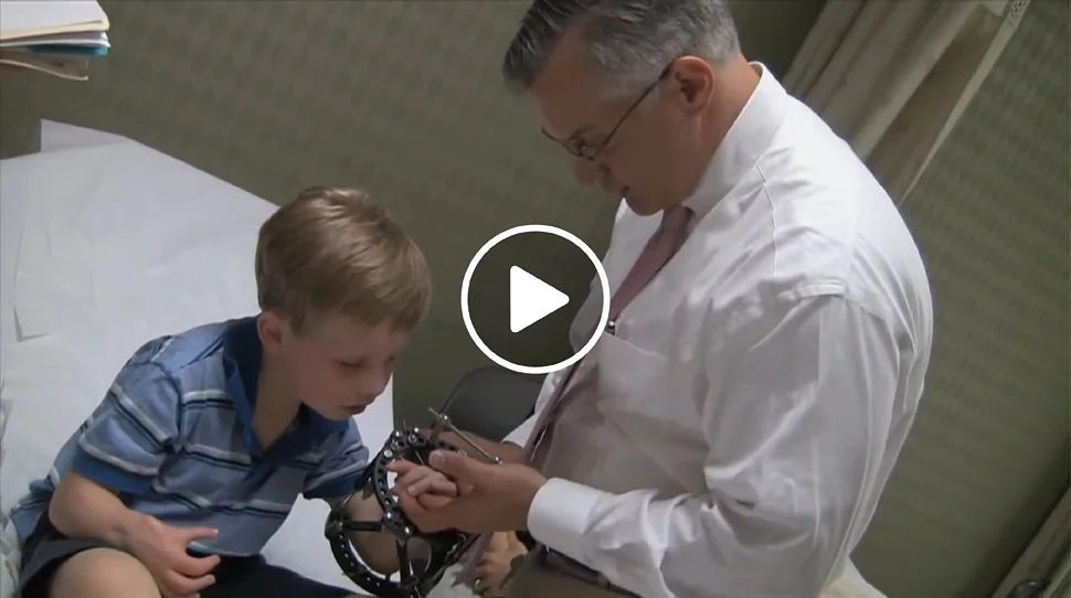 Dr. Shawn Standard checking the hand of a boy patient who is wearing an external fixator on his arm in the International Center for Limb Lengthening clinic