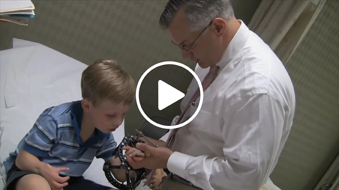 Dr. Shawn Standard checking the hand of a boy patient who is wearing an external fixator on his arm in the International Center for Limb Lengthening clinic