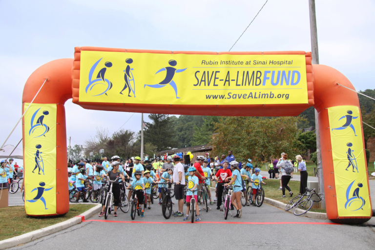 Crowd of bike riders behind Save-A-Limb Fund inflatable starting line at Rubin Institute for Advanced Orthopedics 2016 Save-A-Limb Fund Event