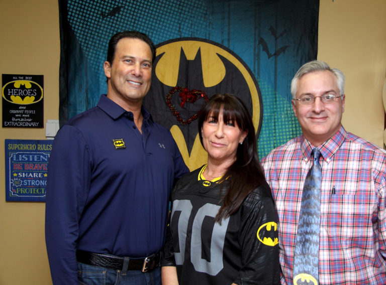 Dr. Shawn Standard poses with the family of Leonard B. “Batman” Robinson in front of Batman banner at the International Center for Limb Lengthening’s Leonard B. “Batman” Robinson Memorial Valentine’s Day Party