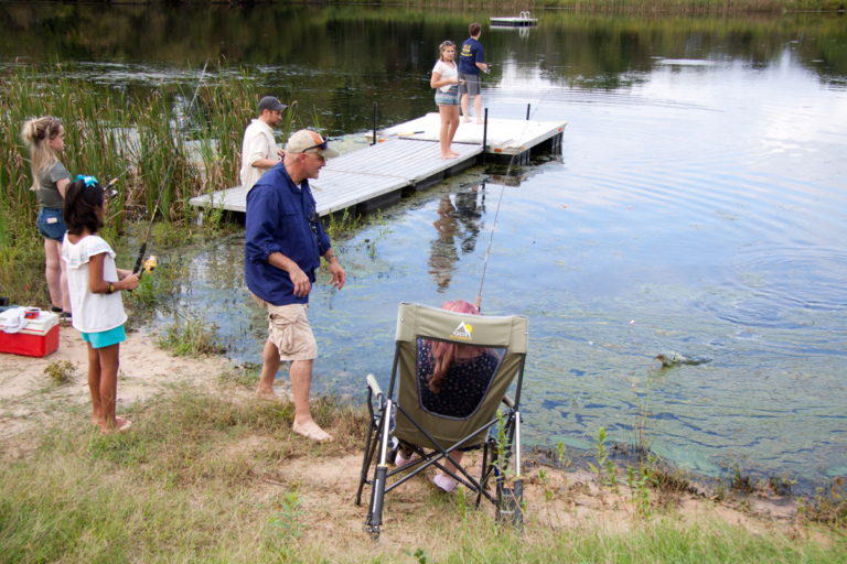 Dr. Shawn Standard fishing with patients and children at pond during Rubin Institute for Advanced Orthopedics 2018 Save-A-Limb Pool Party event