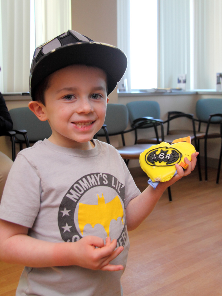 Young boy in Batman shirt holds Batman cookie at the International Center for Limb Lengthening’s Leonard B. “Batman” Robinson Memorial Valentine’s Day Party