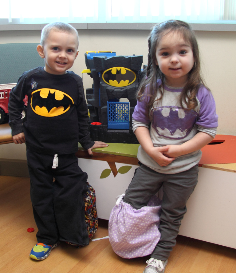 One young girl and one young boy both wearing Batman shirts and with covered external fixators on opposite legs play with a Batman toy at the International Center for Limb Lengthening’s Leonard B. “Batman” Robinson Memorial Valentine’s Day Party