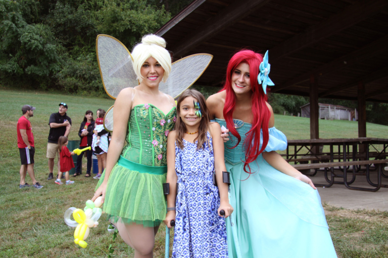 Young girls with facepaint and forearm crutches poses with Tinker Bell and the Little Mermaid at Rubin Institute for Advanced Orthopedics 2016 Save-A-Limb Fund Event