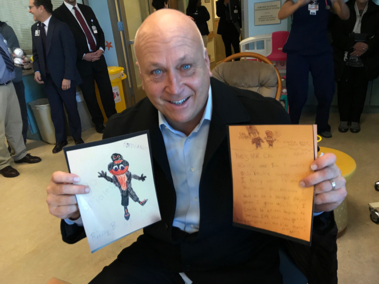 Cal Ripken holds up children’s artwork at Cal Ripken at Herman & Walter Samuelson Children