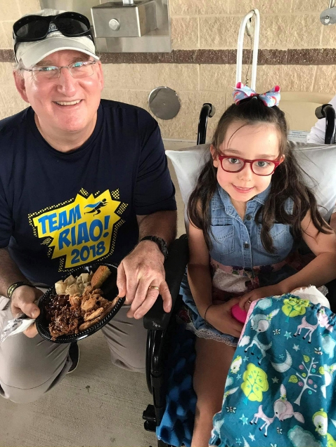 Dr. John Herzenberg with young girl in wheelchair at Rubin Institute for Advanced Orthopedics 2018 Save-A-Limb Pool Party event