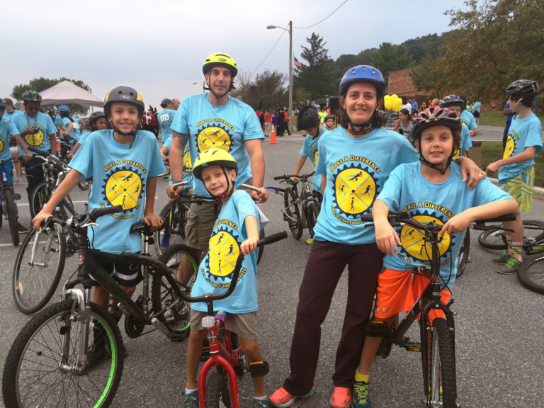 2 adults and 3 children in Save-A-Limb blue event shirts on bikes at Rubin Institute for Advanced Orthopedics 2016 Save-A-Limb Fund Event