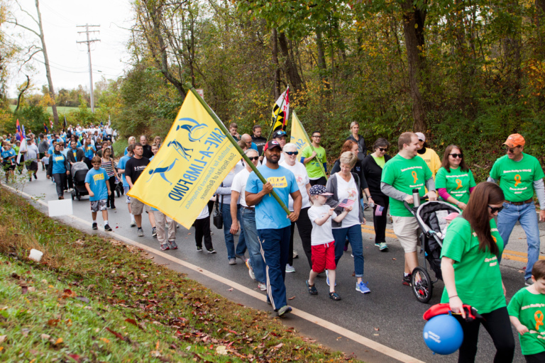 Earl Cole the winner of Survivor: Fiji reality television show and founder of Perthes Kids Foundation, holds Save-A-Limb flag among dozens of participants during the family fun walk at Rubin Institute for Advanced Orthopedics 2017 Save-A-Limb Fund Event