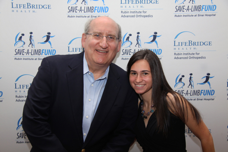 Dr. John Herzenberg and girl in front of Save-A-Limb Fund photo backdrop at Rubin Institute for Advanced Orthopedics 2016 Save-A-Limb Fund Dinner