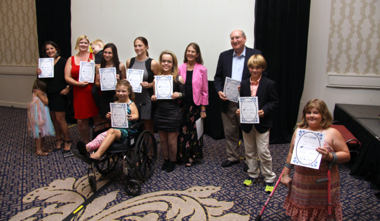 Dr. John Herzenberg with multiple patients, one using forearm crutches and one in a wheelchair, and a few of their family members holding award certificates at Rubin Institute for Advanced Orthopedics 2016 Save-A-Limb Fund Dinner