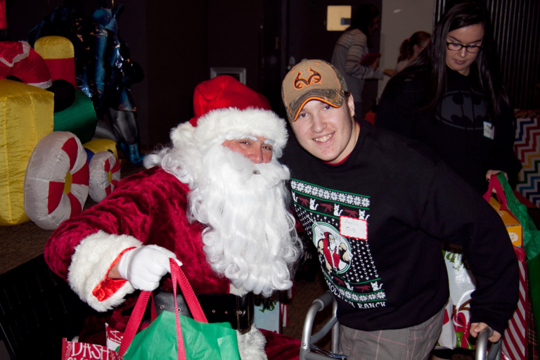 Boy with walker poses for a picture with Santa at the International Center for Limb Lengthening pediatric holiday party