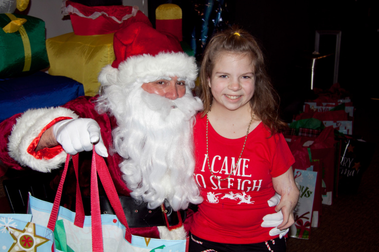 Girl patient takes picture with Santa and present at the International Center for Limb Lengthening pediatric holiday party