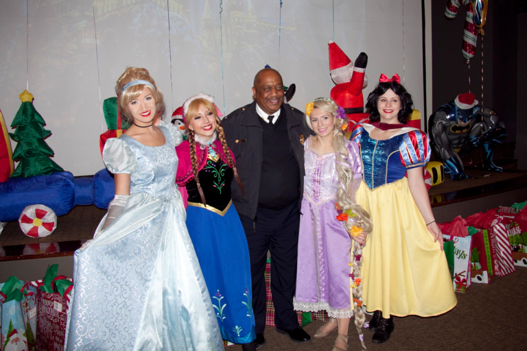 Firemen takes picture with Disney princesses, Cinderella, Anna, Rapunzel, and Snow White at the International Center for Limb Lengthening pediatric holiday party