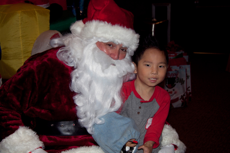 Young boy with covered external fixator on arm sits on Santa’s lap for a picture at the International Center for Limb Lengthening pediatric holiday party