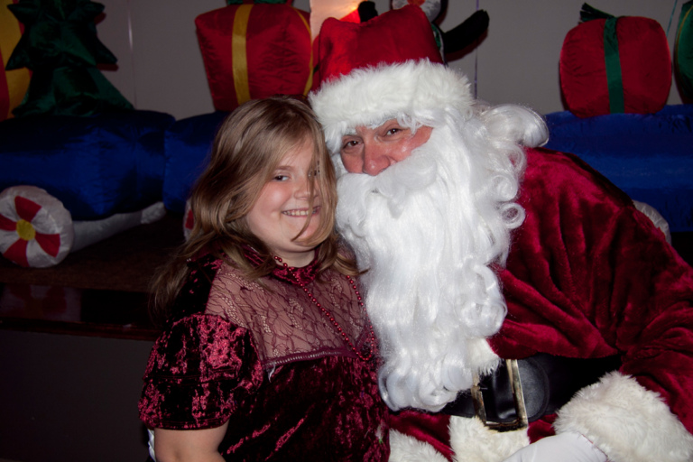 Girl smiles with Santa for a photo at the International Center for Limb Lengthening pediatric holiday party