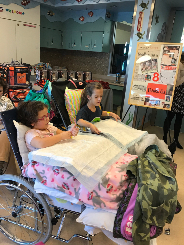 2 young girls in wheelchairs in front of Baltimore Orioles giveaways at Cal Ripken event at Herman & Walter Samuelson Children
