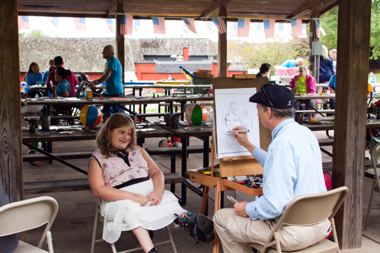 Young girl with leg brace has caricature done by artist at Rubin Institute for Advanced Orthopedics 2017 Save-A-Limb Fund Event