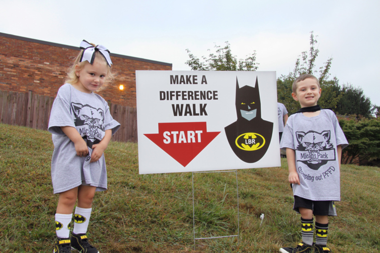 2 young children wearing Batman attire standing with Batman “Make a Difference Walk” starting sign at Rubin Institute for Advanced Orthopedics 2016 Save-A-Limb Fund Event