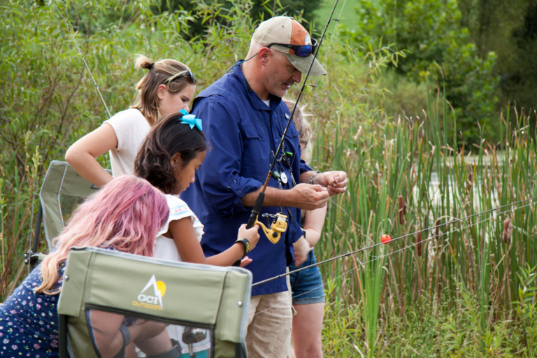Dr. Shawn Standard fishing with girls at pond during Rubin Institute for Advanced Orthopedics 2018 Save-A-Limb Pool Party event