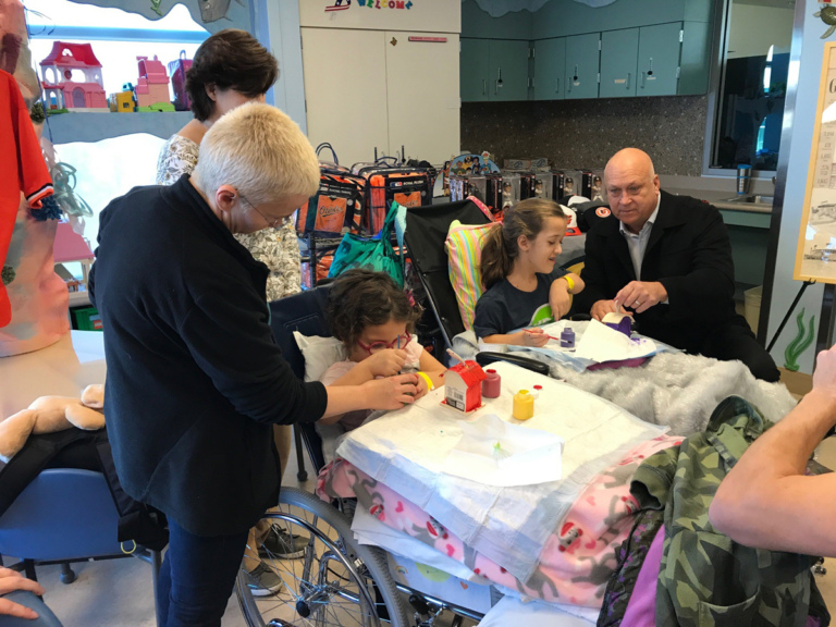 Cal Ripken helps 2 young girl patients in wheelchairs paint birdhouses at Cal Ripken at Herman & Walter Samuelson Children