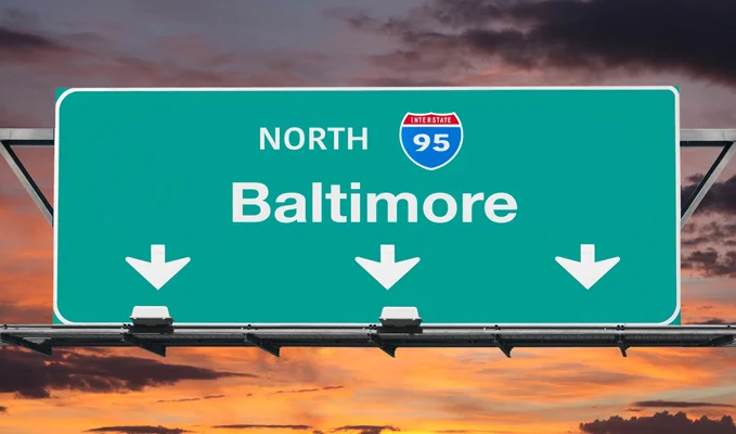 Highway sign for Interstate 95 to Baltimore against a cloudy sunset