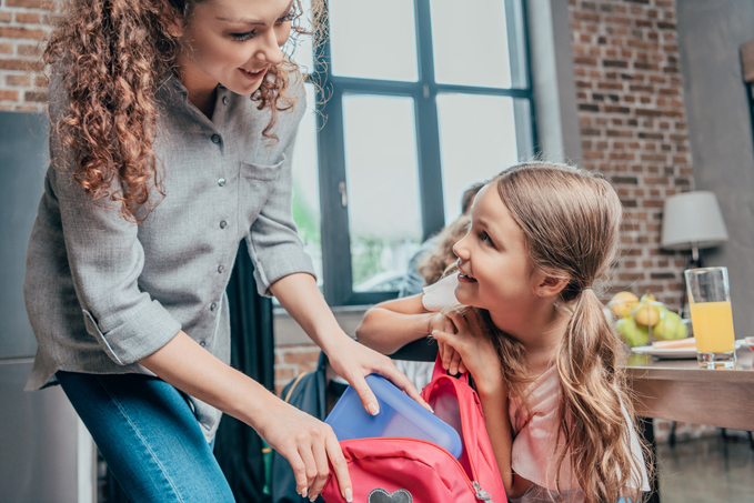 Mother giving school lunch to daughter