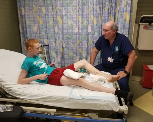 Gary reclining back with leg elevated in clinic bed while talking to Dr. John Herzenberg
