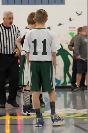 Jeffrey in a number 11 basketball uniform from behind showing him wearing a shoe lift